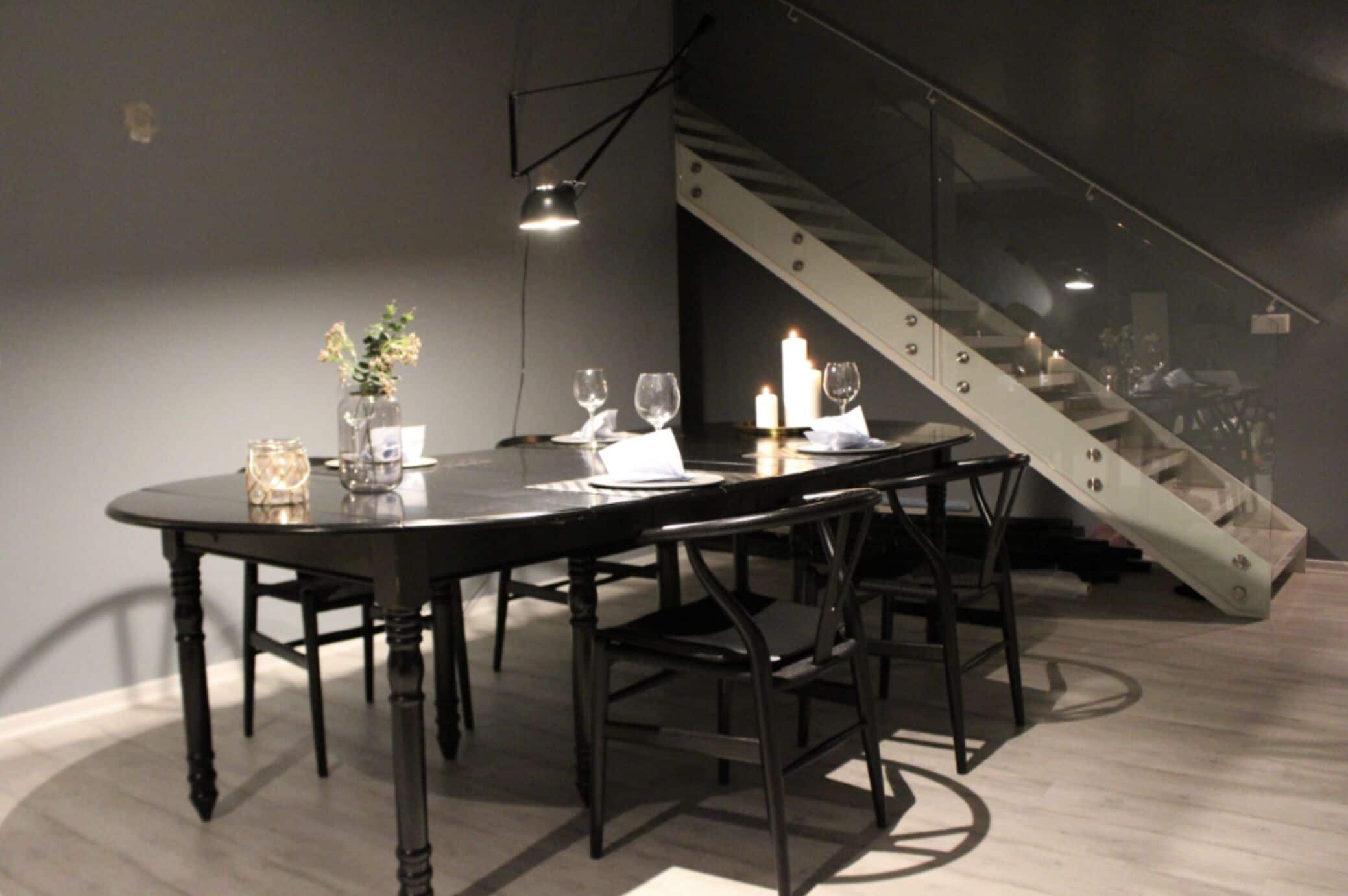 A dining area with a round table, chairs, candles, and a staircase.