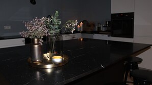 Een keuken met een marmeren aanrecht, een vaas met bloemen en een brandende kaars.