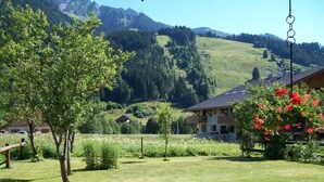 Un paisaje rural con una casa, un árbol y una montaña al fondo.