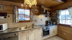 Una cocina con paredes de madera, un lavamanos de acero inoxidable, un lavavajillas Bosch y un horno empotrado.