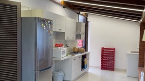 A compact kitchen with a refrigerator, microwave, and stove. - Vacation home Andreina (the yellow) (Ognina)