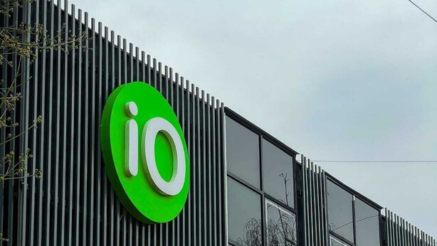 A building with a prominent green logo and vertical slats on the facade. - IO hotel Bishkek (Bishkek)