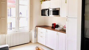 Une cuisine moderne avec des meubles blancs, un plan de travail en bois et une fenêtre équipée de stores.