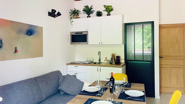 Un espacio habitable compacto con kitchenette, comedor y sofá.
