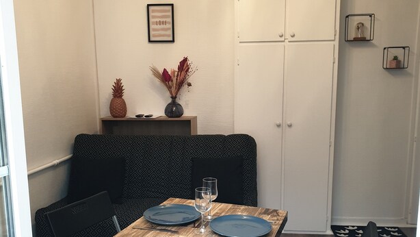 Ein gemütlicher Essbereich mit einem Holztisch, zwei blauen Tellern und einer Vase mit getrockneten Blumen.