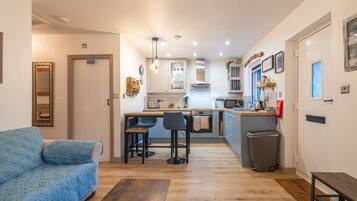 Un espacio habitable compacto con kitchenette, un sofá y zona de comedor.