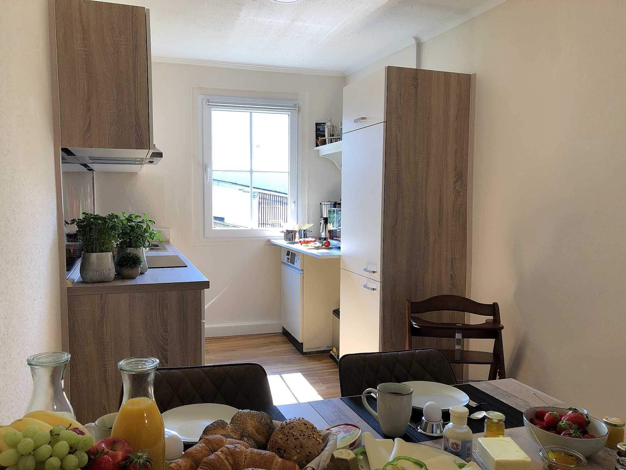Eine kompakte Küche mit Essbereich, mit einem Fenster und Blick, einer kleinen Kühlschrank und einem Tisch gedeckt mit Speisen.