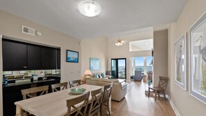 A spacious living area with a dining table, chairs, a sofa, and a view of the ocean. - Escape to paradise at Palm Beach Club #217/Sound Front Condo! (Pensacola Beach)