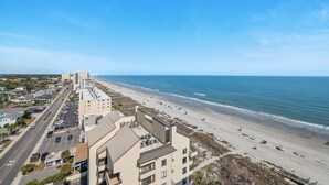 Un hôtel situé sur la côte, avec vue sur la plage, plusieurs étages et un parking.