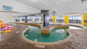 Une piscine intérieure avec un panneau d’avertissement indiquant une faible hauteur sous plafond, un panneau indiquant une profondeur minimale de 3 pieds pour les plongeons, et un sol carrelé.