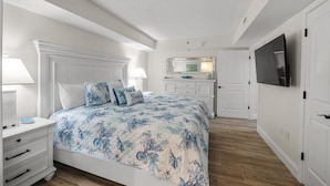Une chambre à coucher comprenant un lit, des tables de chevet, une commode, un téléviseur et un miroir dans la salle de bain.