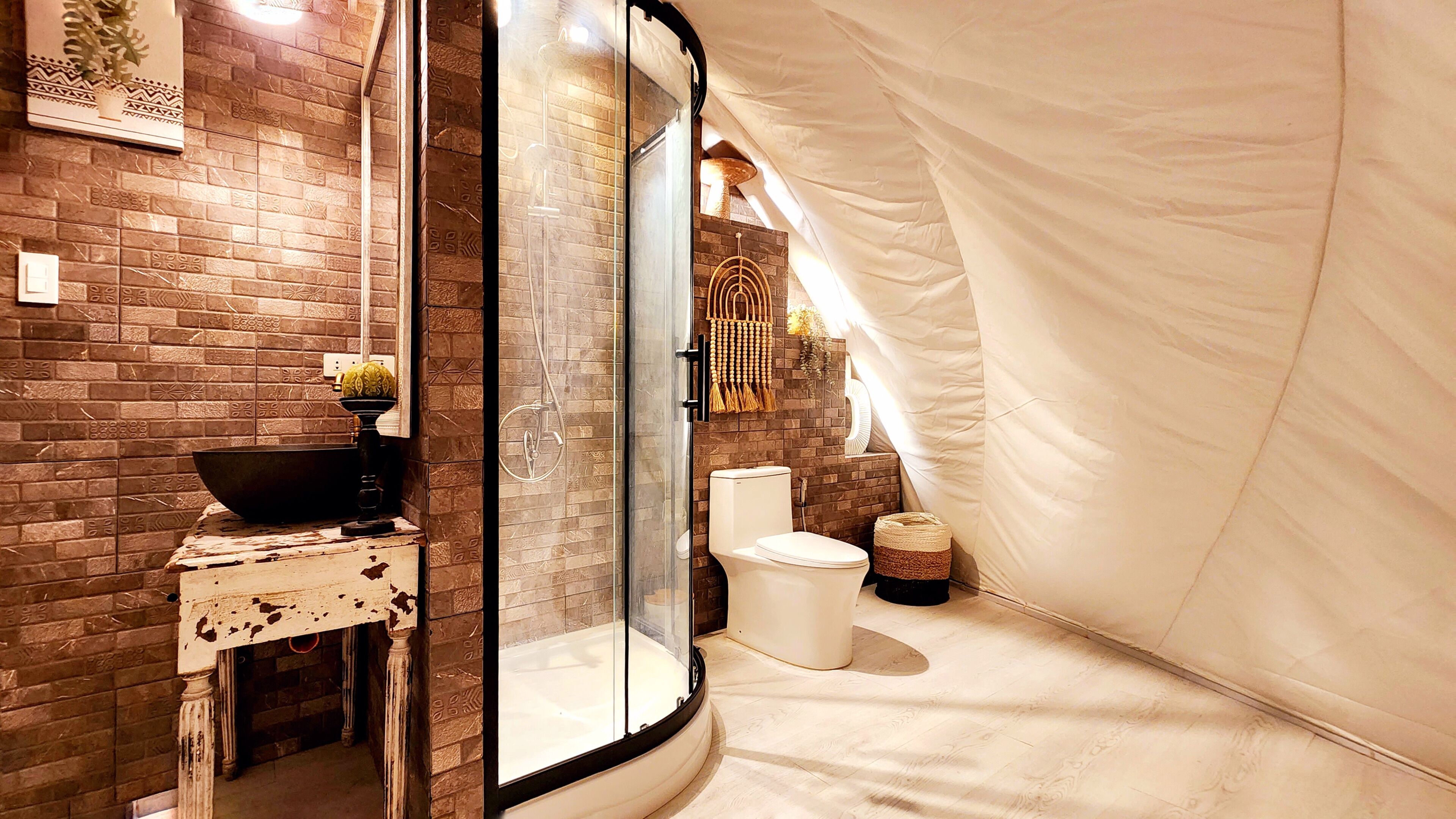 Une salle de bain avec une douche à parois de verre, des toilettes blanches et un lavabo agrémenté d’un récipient décoratif.