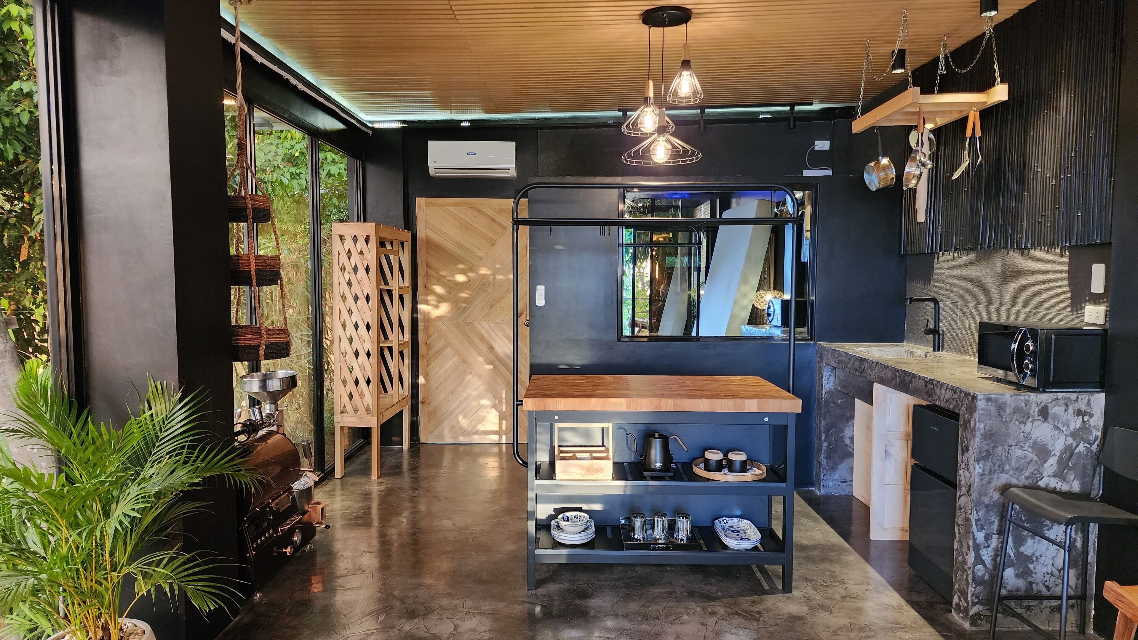 A modern kitchen with a wooden countertop, black shelving unit, and hanging pendant lights.