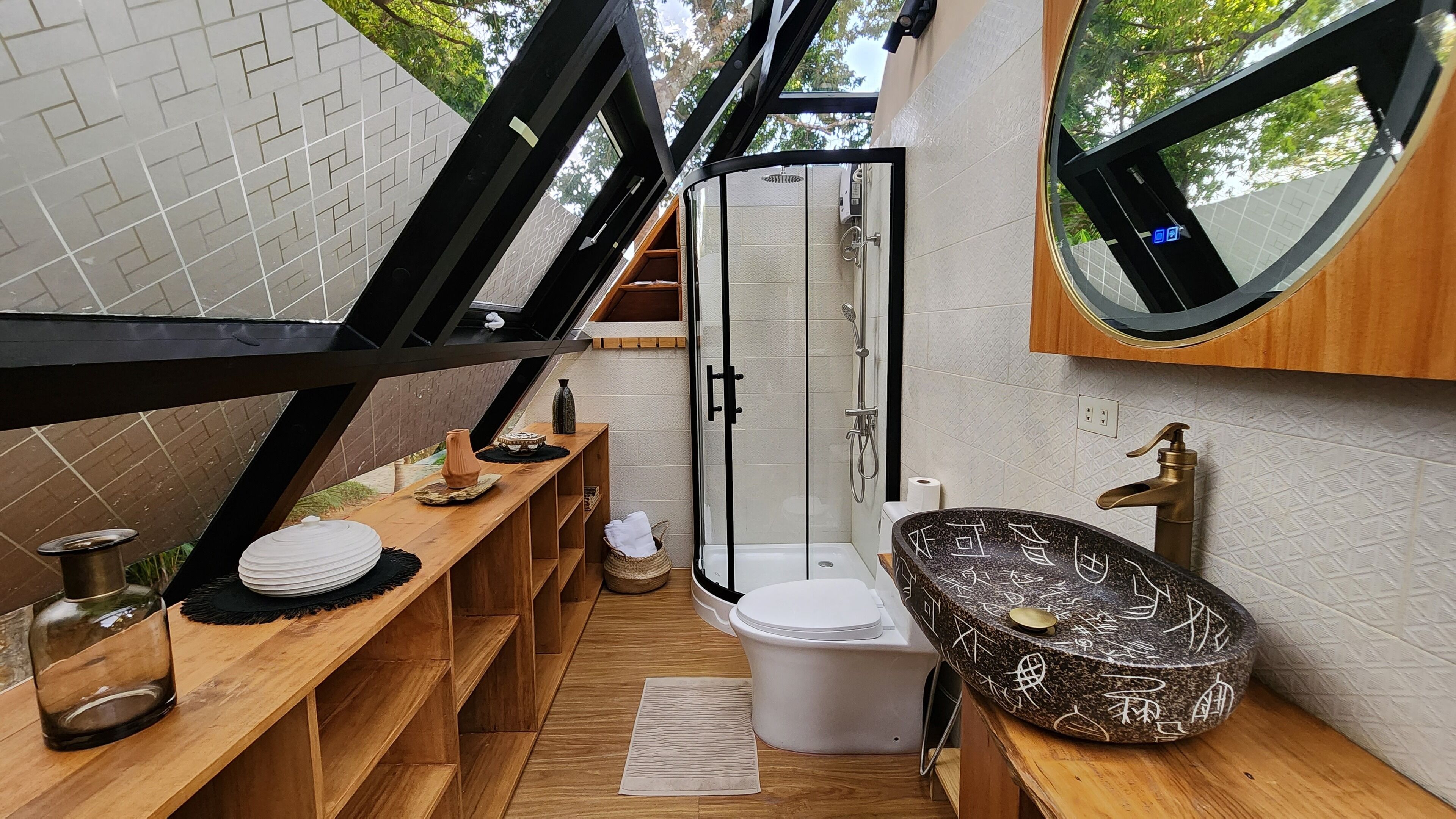 A compact bathroom with a shower, toilet, and a unique black basin with white designs.