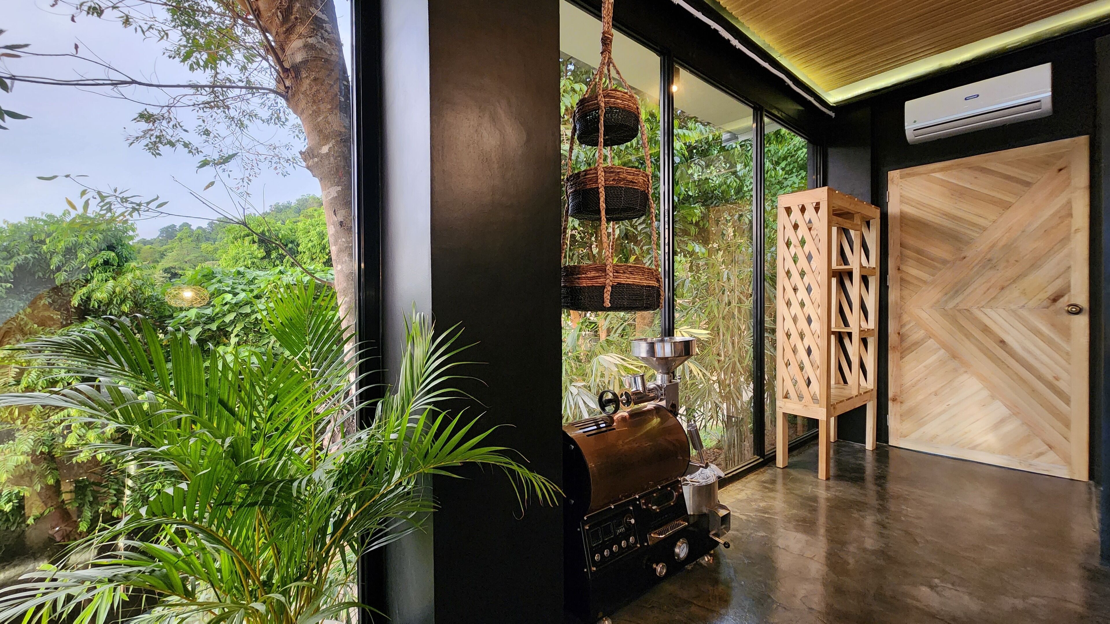 A modern room with a large window, a wooden door, and a grill outside.