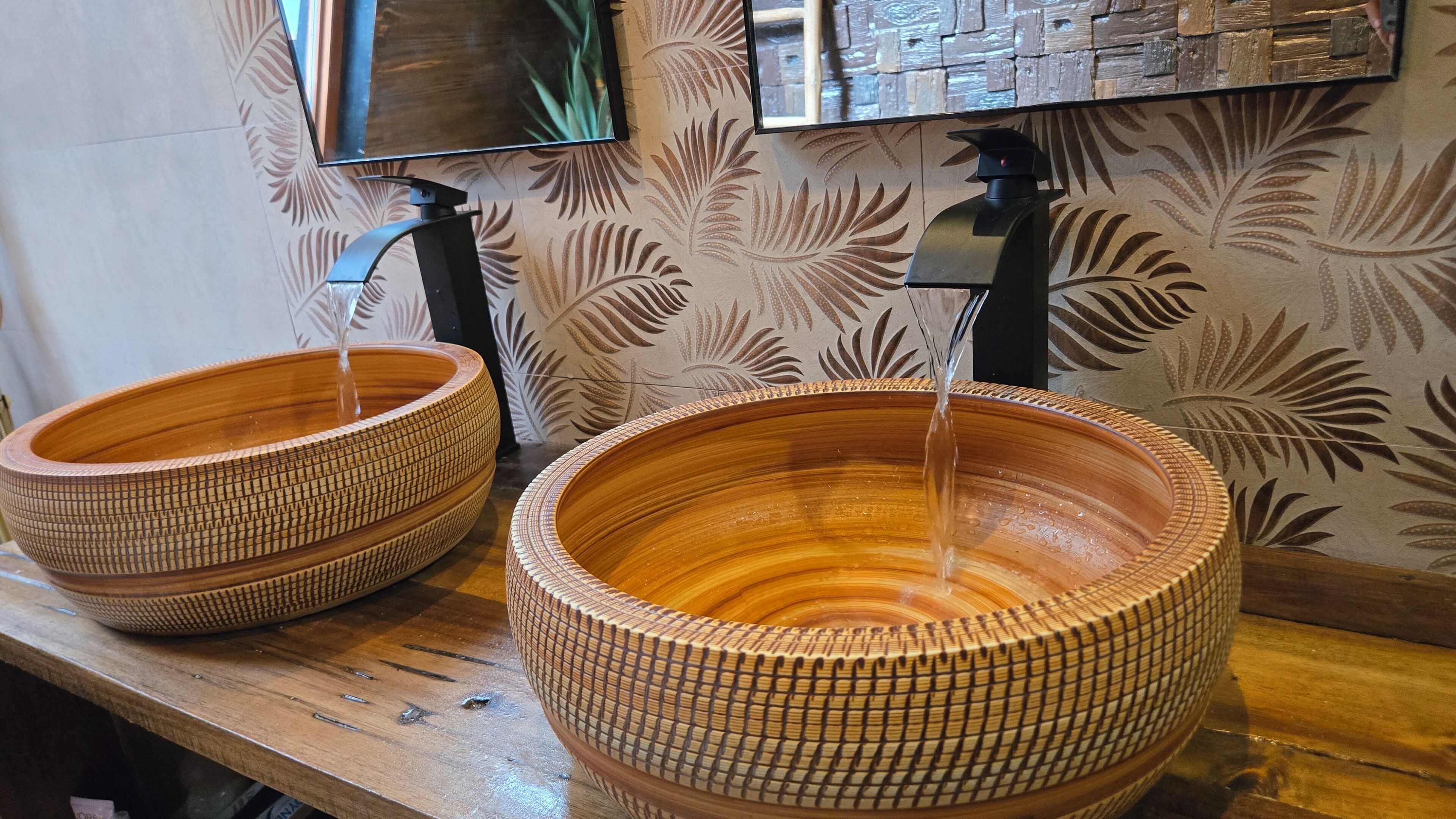 Two large, woven ceramic basins with water flowing into them, placed on a wooden surface.