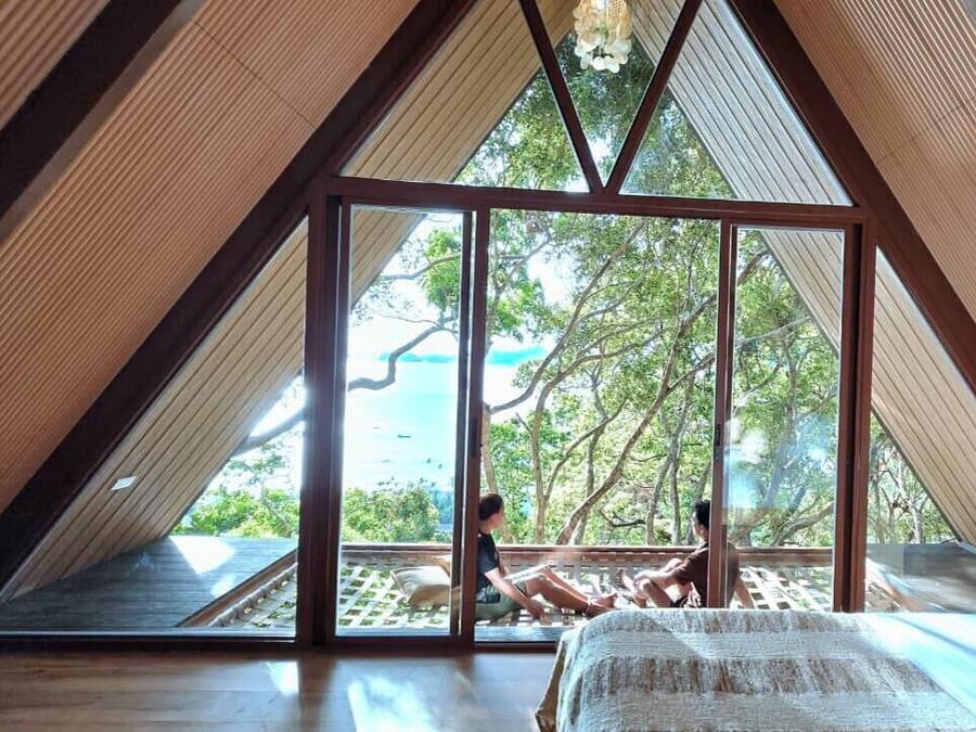 A room with a sloped ceiling and large windows, offering a view of the outdoors.