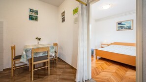 A room with a bed, a table with chairs, and a small window with curtains. - Little apartment near the beach - Aleks 3 (Umag)