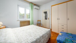 A bedroom with a bed, a chair, a wardrobe, and a window with curtains. - Little apartment near the beach - Aleks 3 (Umag)