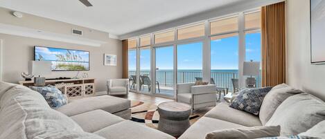 Relax in this stylish living room with a large sectional sofa, flat-screen TV, and ocean views from the balcony.
