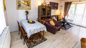 Un salon comprenant une table à manger, un canapé en cuir, une bibliothèque et un tableau accroché au mur.