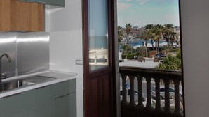 A modern kitchen with a built-in sink and a view of a balcony with a railing and palm trees.