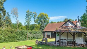 Une maison de campagne au toit en tuiles, dotée d’un espace barbecue et d’une petite terrasse.