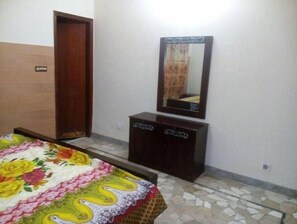 A bedroom with a bed, a dresser, a mirror, and a door.