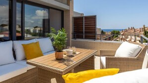 Eine Dachterrasse mit einer Couch, einem Esstisch und Stühlen.