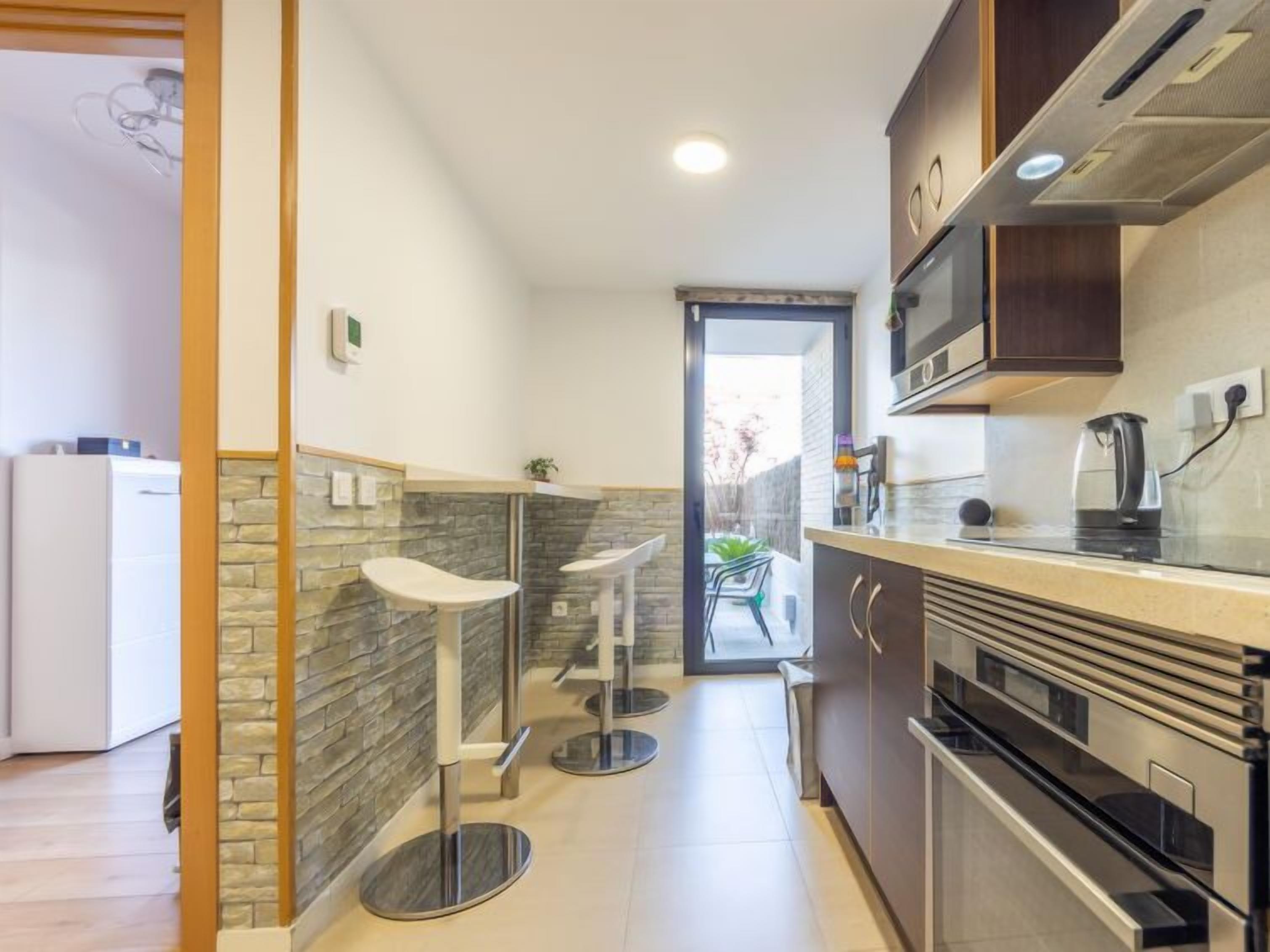 A compact kitchen with a stone accent wall, a built-in oven, and a coffee maker on the counter.