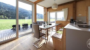 Una cucina moderna con ampie finestre, travi in legno e vista su un paesaggio verde.