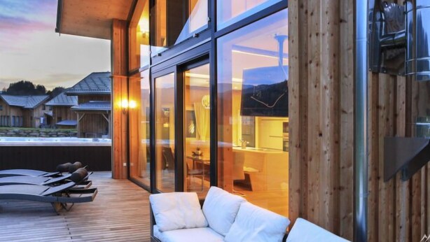 Zona relax esterna moderna con un decking in legno, una poltrona e poltrone lounge.