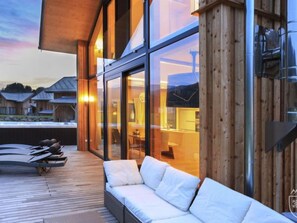 Un espace extérieur moderne aménagé avec une terrasse en bois, un canapé et des fauteuils de relaxation.