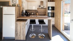 A modern kitchen with a central island, stainless steel appliances, and a wooden ceiling.