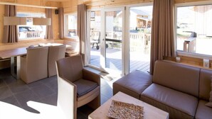 A wooden interior with a dining area, sofa, and a view of the outside.