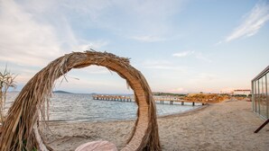 Una playa con un arco de paja y una silla de mimbre.