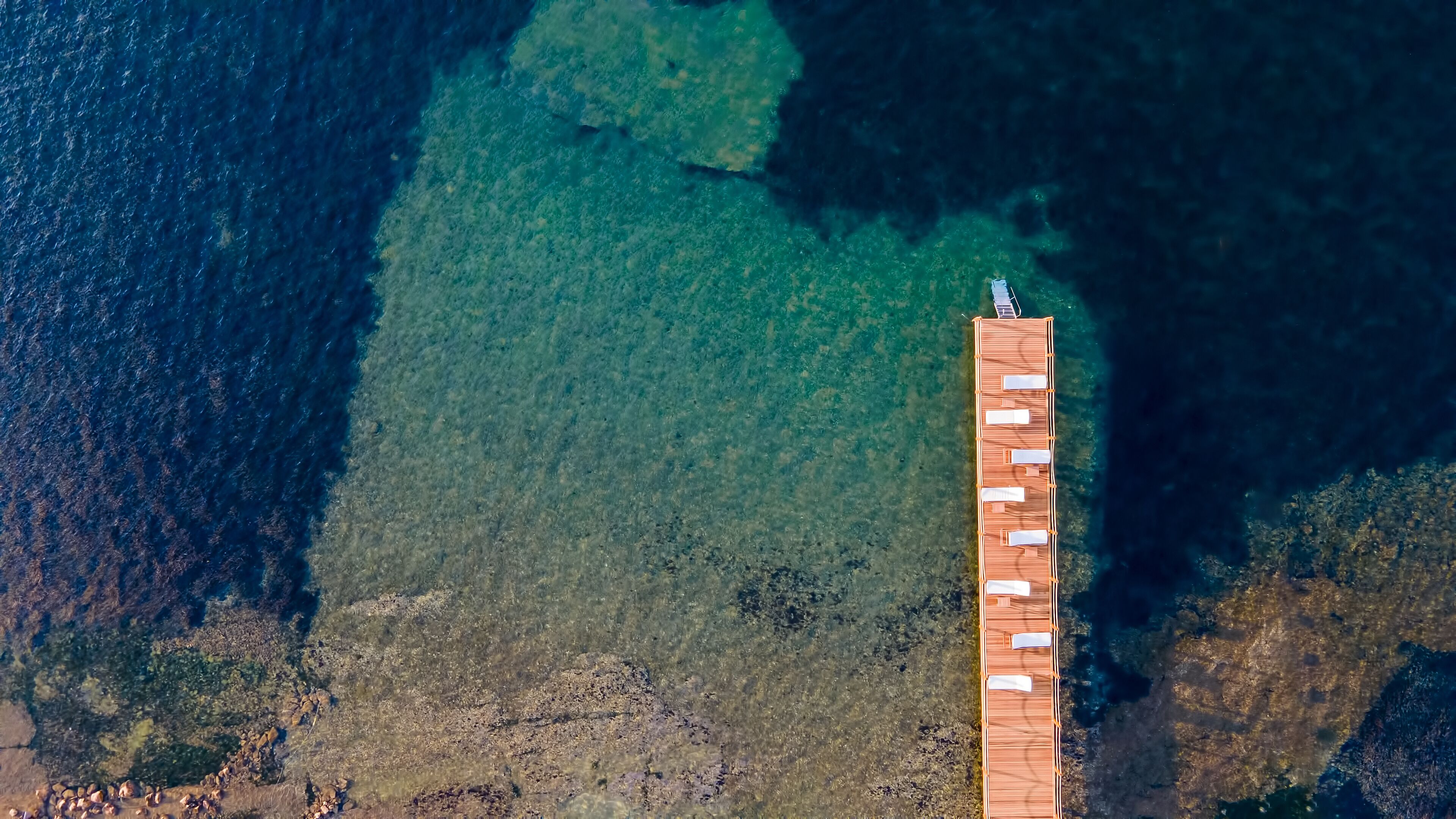 An aerial view of a pier with a row of sun loungers.
