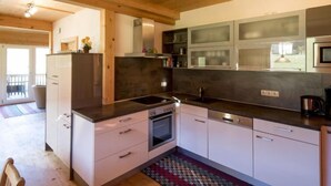 Una cocina moderna con armarios blancos, encimera negra y electrodomésticos de acero inoxidable.