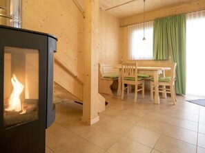Cozy room with stove, dining table, and wooden paneling.