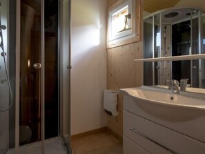 Bathroom features a glass shower enclosure, handheld showerhead, and a sink with a modern faucet.