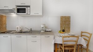 Una cucina moderna con mobili bianchi, un forno a microonde, una macchina da caffè e un'area pranzo con tavolo e sedie.