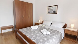 Una camera da letto con un letto, un armadio in legno, comodini e un quadro appeso al muro.