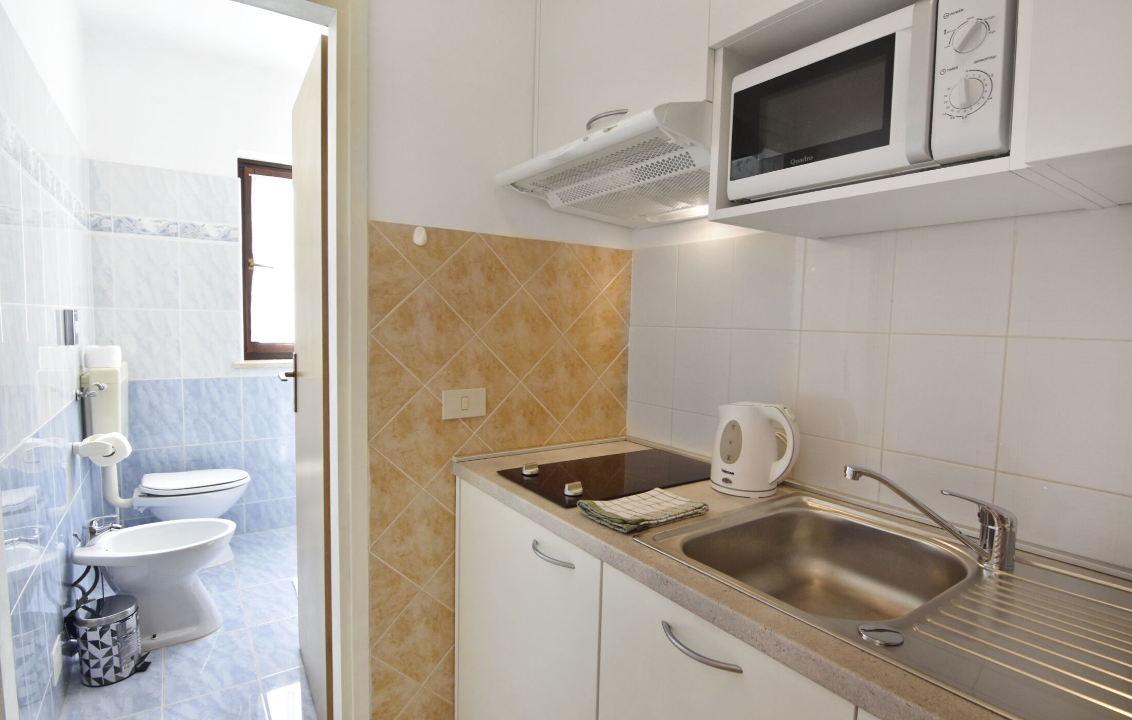 A modern kitchen with a built-in microwave, a stainless steel sink, and a countertop with a kettle.