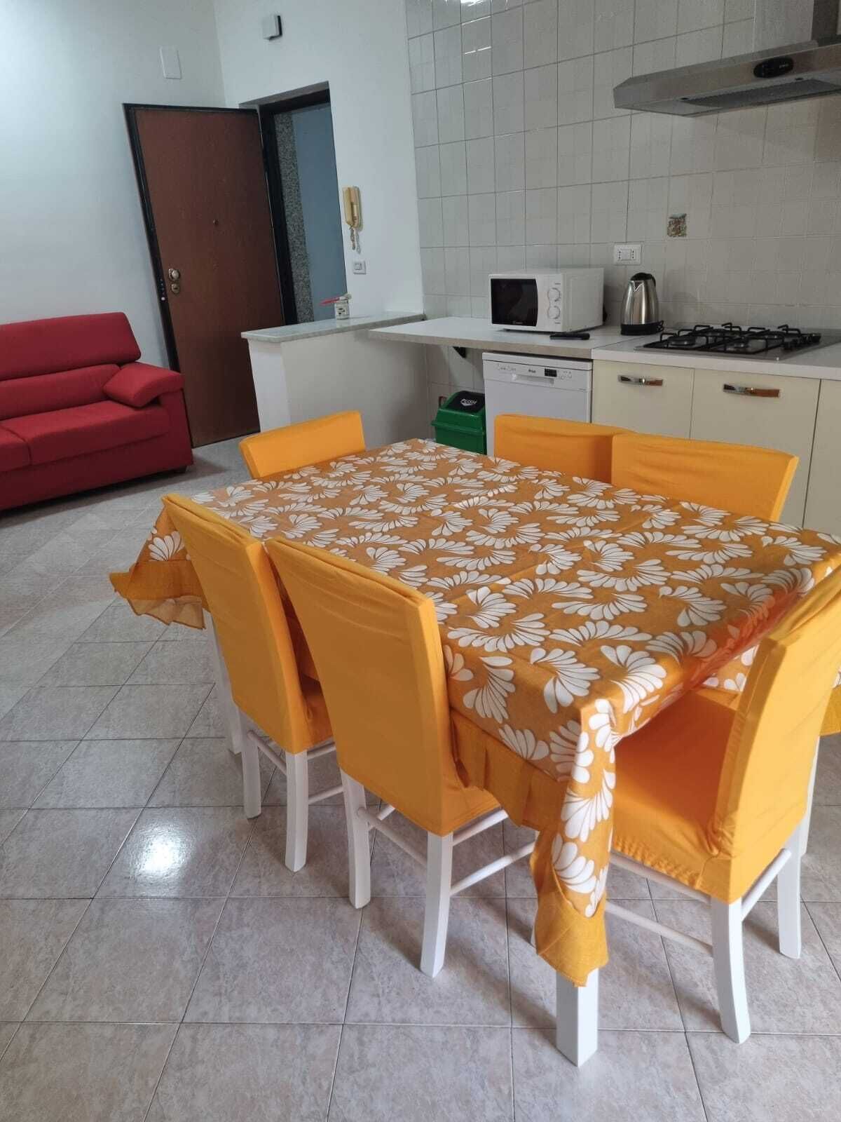 A compact kitchen with a microwave, stove, and sink. A dining table with chairs is set up in the room.