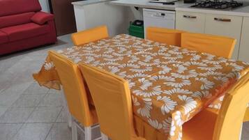 A compact kitchen with a microwave, stove, and sink. A dining table with chairs is set up in the room.