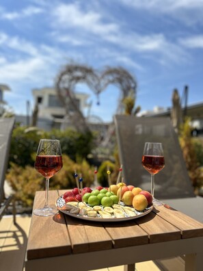 A wooden table with two wine glasses and a fruit platter. - No 48 Alaçatı (Cesme)
