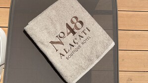 A table with a plate of fruit, two glasses of red wine, and a towel with "No 48 Alacati Boutique Hotel" printed on it. - No 48 Alaçatı  (Cesme)