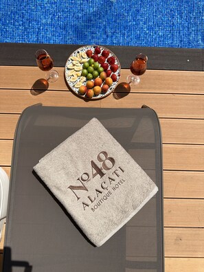 A table with a plate of fruit, two glasses of red wine, and a towel with "No 48 Alacati Boutique Hotel" printed on it. - No 48 Alaçatı (Cesme)