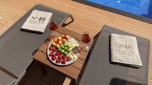 A poolside table with a plate of fruit, two glasses of red wine, and a towel with "No 18 Alacati Boutique Hotel" printed on it. - No 48 Alaçatı  (Cesme)