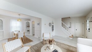 A spacious living room with a dining area, a staircase, and a kitchen.